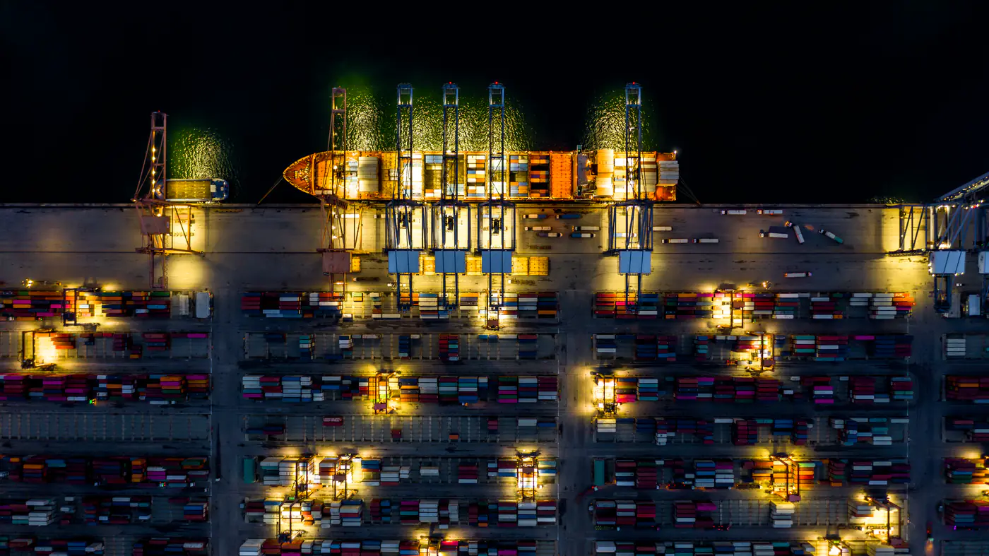 Container ship at an industrial port at night, seen from above